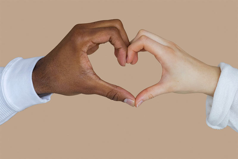 A black left hand and white right hand join to make a heart