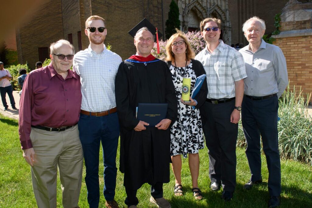 A graduate poses with his family and friends outside LSTC's Commencement 2023