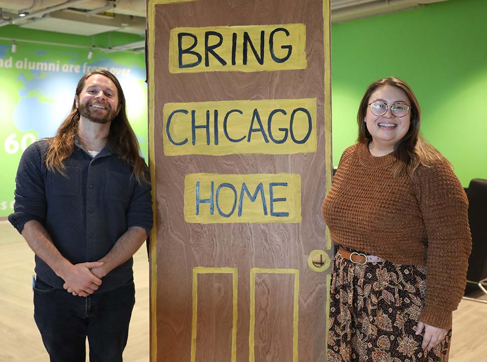 Bring Chicago Home Townhall attendees pose by a makeshift door that reads Bring Chicago Home.