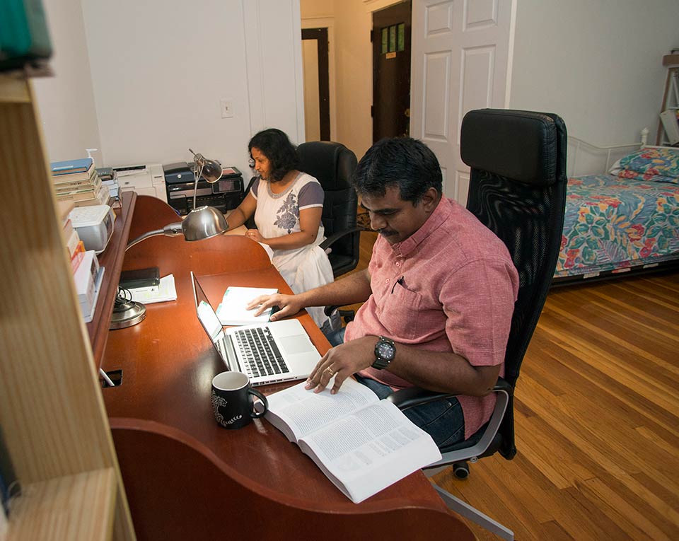 Two LSTC students studying at desks in their apartment.