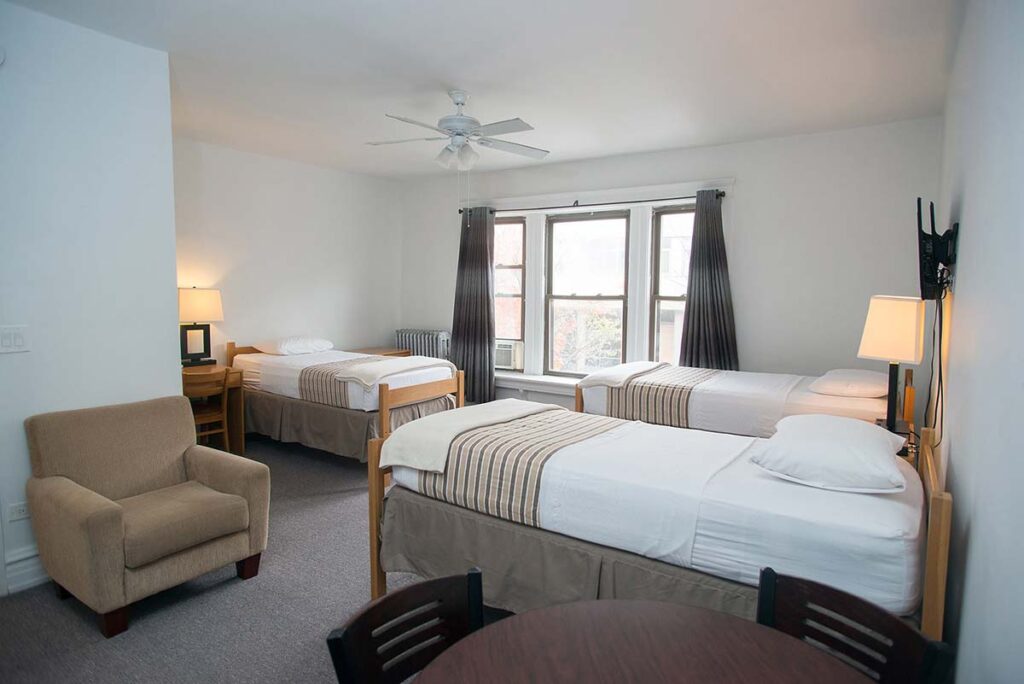 A bedroom with three beds and a chair in LSTC guest housing.