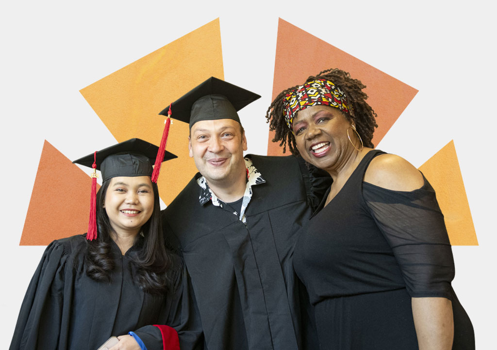 Two graduates in cap and gown posing with a friend.