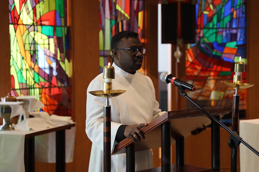 A preacher in white robes speaking at the podium in the LSTC Chapel.