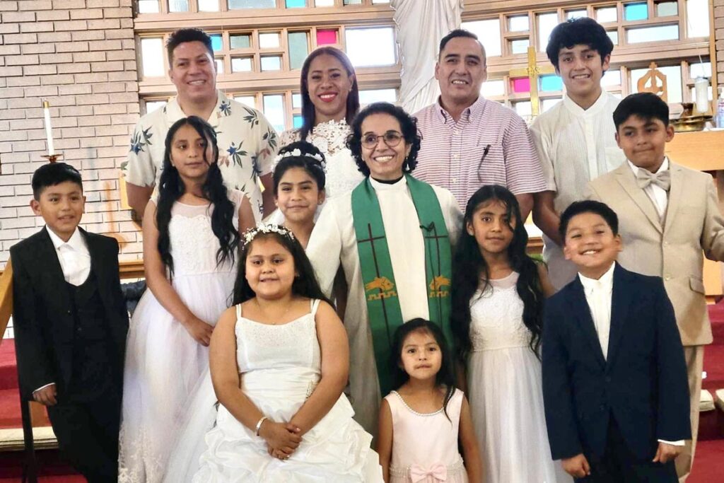 Rev. Dr. Patrica Cuyatti smiling in a group shot during a First Communion/Confirmation service.