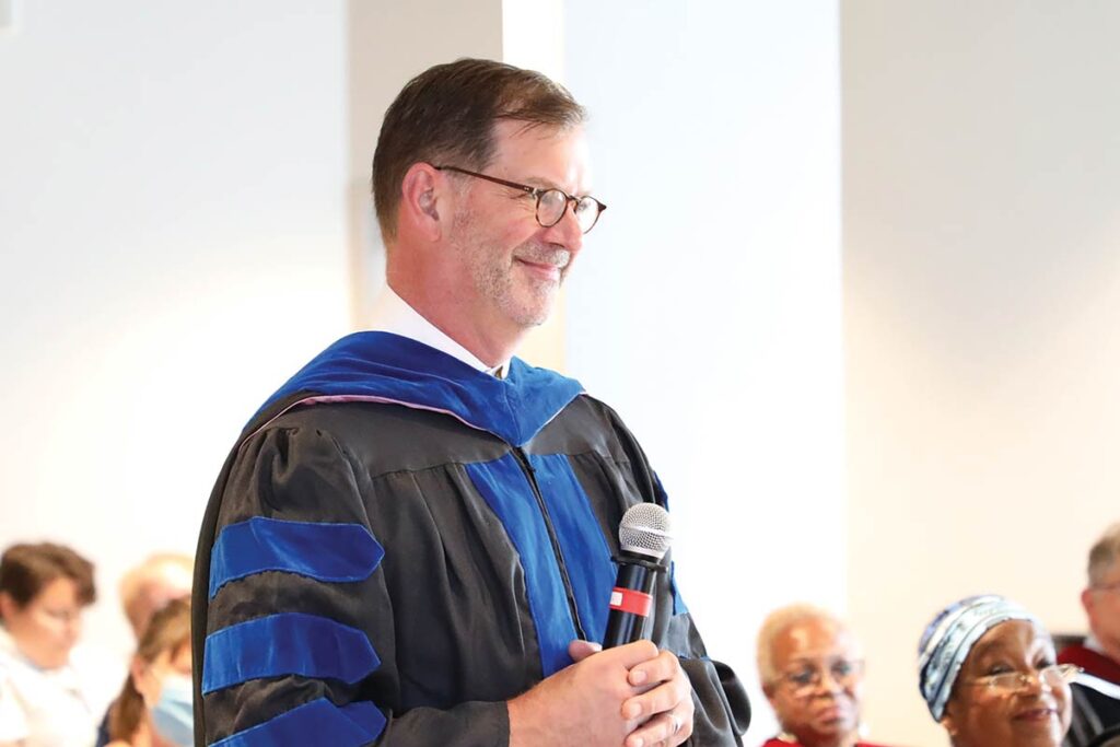 Rev. Dr. Christian Scharen hold a microphone while leading worship in the LSTC Chapel.