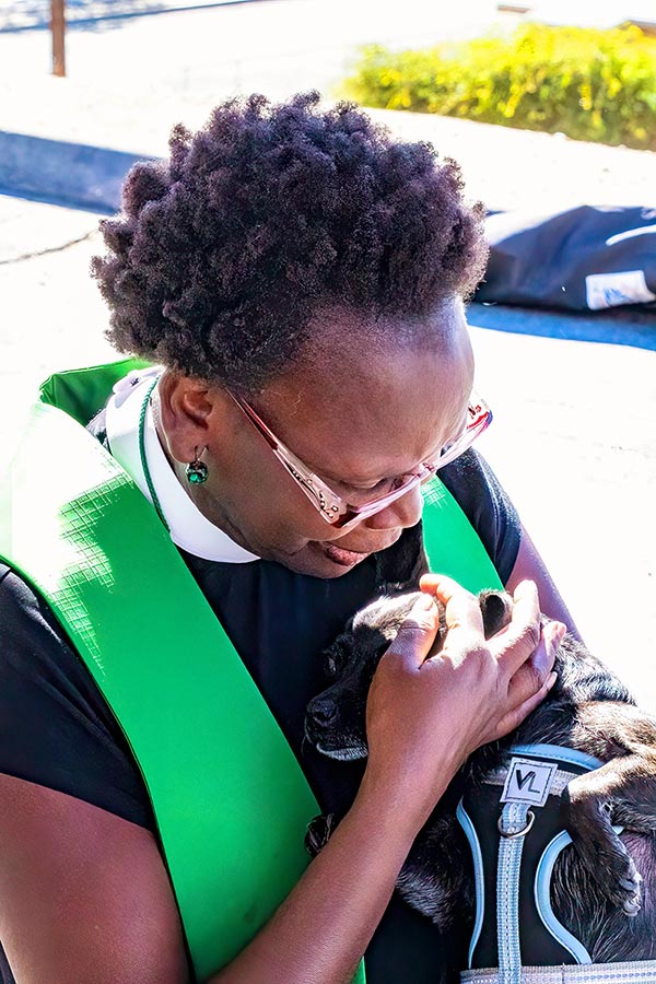 Rev. Dr. Mary Tororeiy blessing a dog.