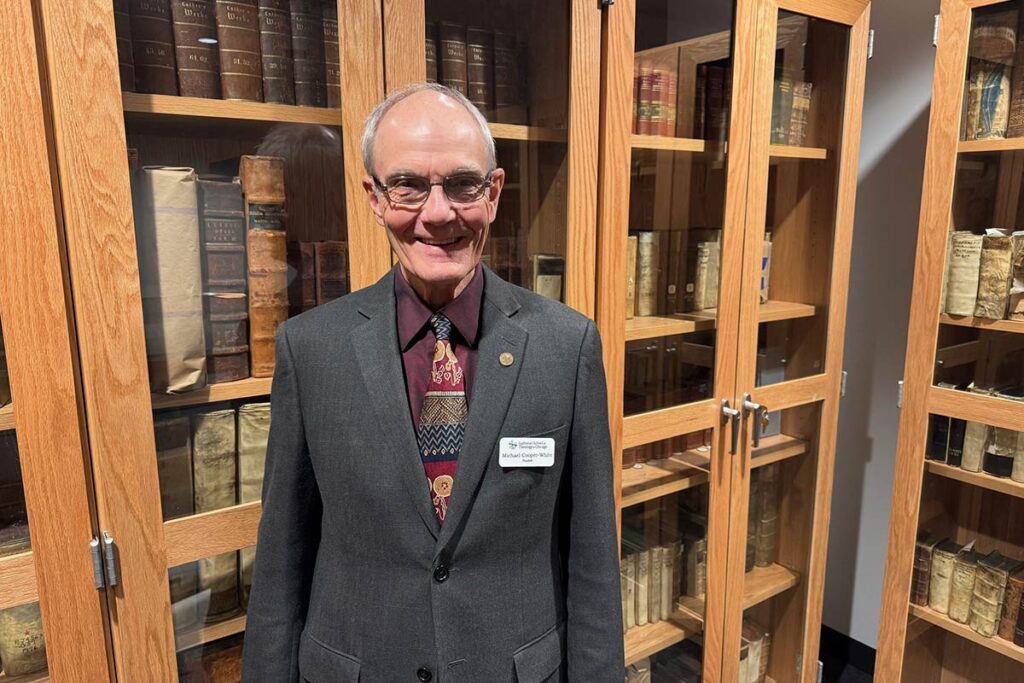Interim President Michael Cooper-White with shelves of books behind him in LSTC's Rare Book Room.