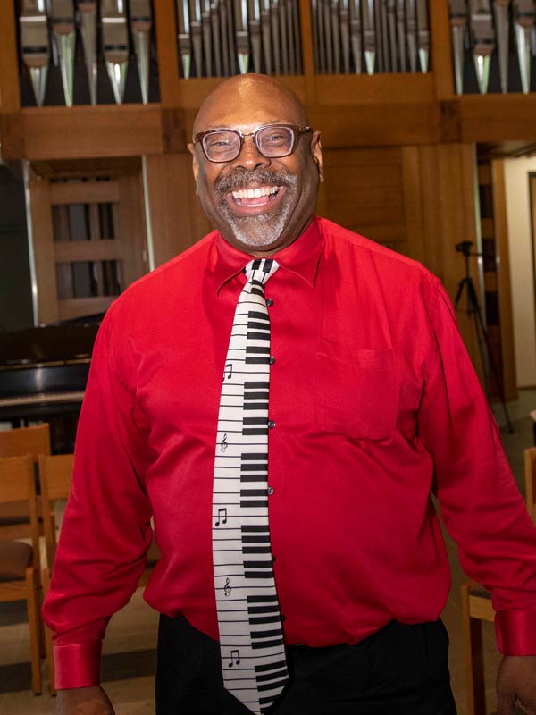 Conductor Dr. Keith Hampton smiling in front of the Manz Organ.