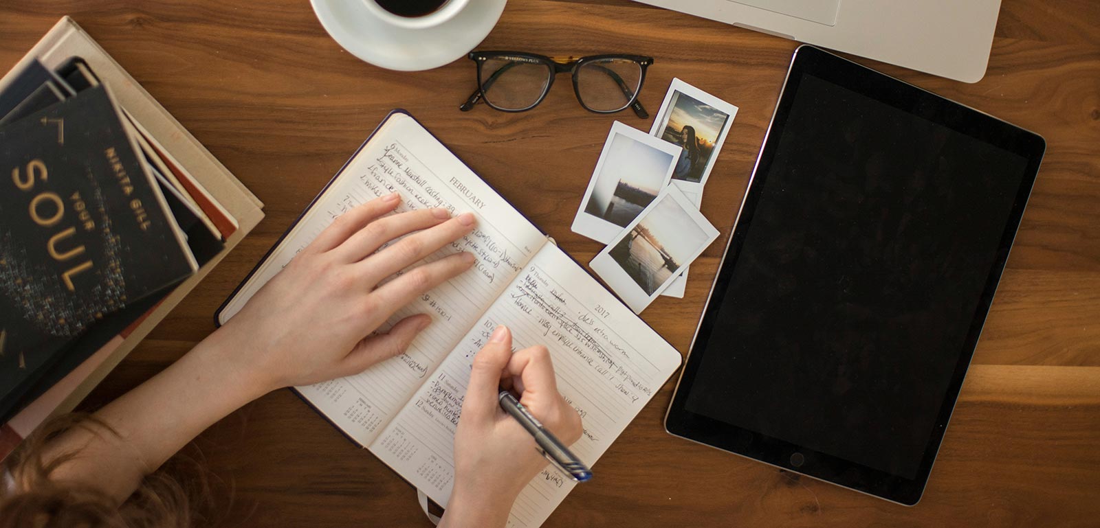 A student writing in a notebook with research materials around her.