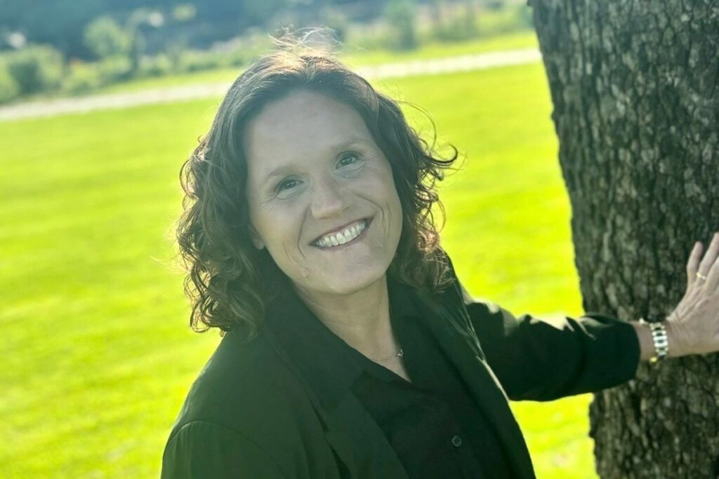 Author and Alum Bonnie J. Flessen poses by a tree.