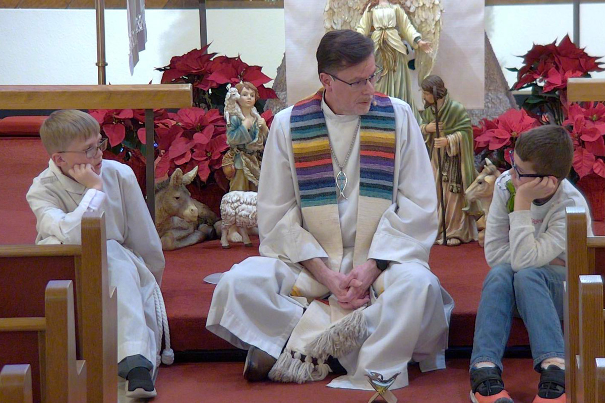 Kurt Fangmeier talking in his congregation with two young parishioners.