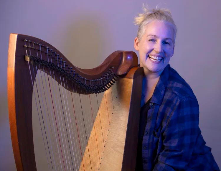 Reverend April Stace poses with their harp.